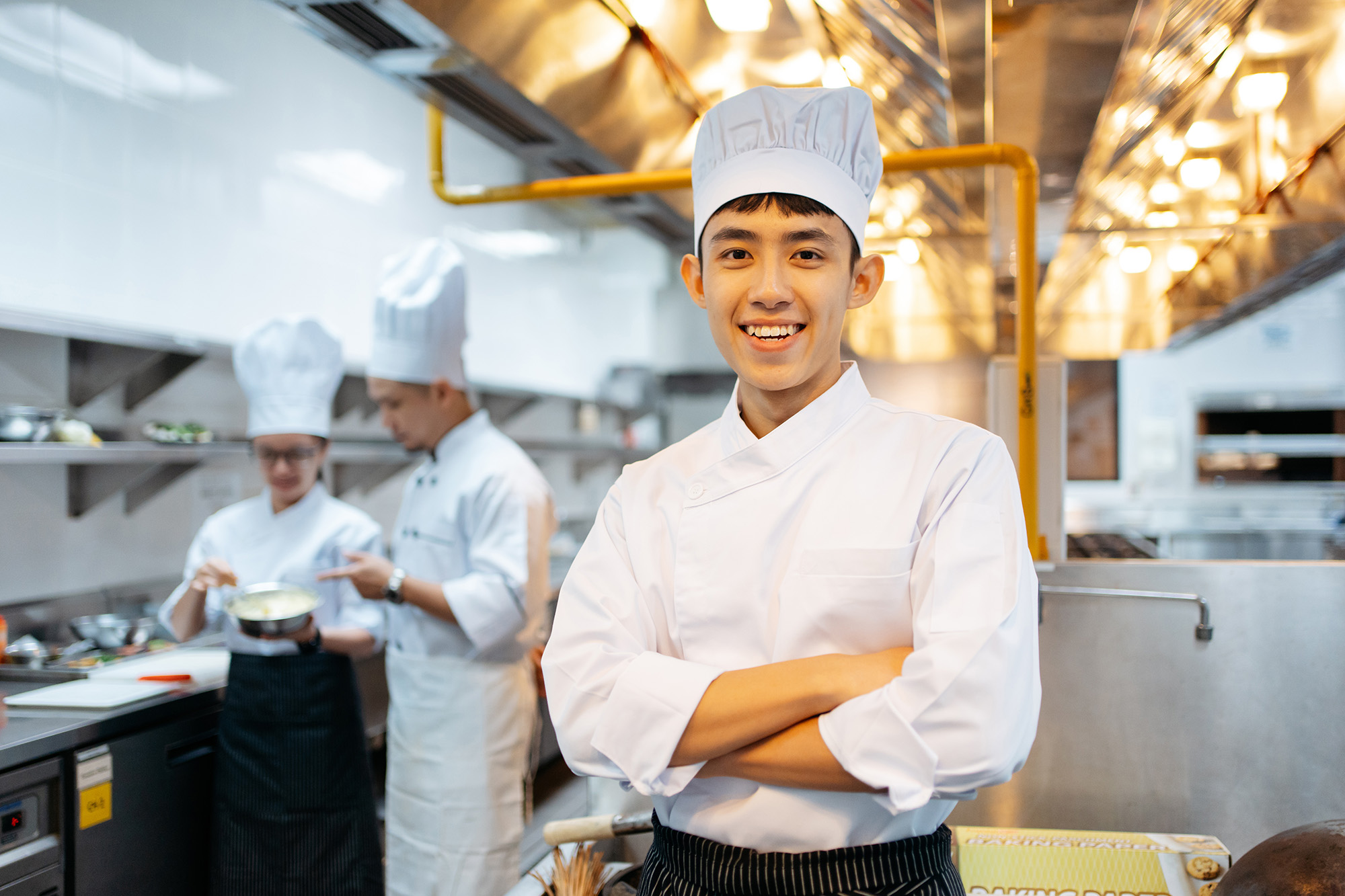 Young asian cook standing in a kitchen of a restaurant